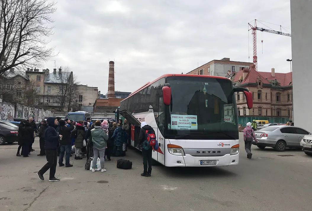 People grouped around a bus waiting to get on.